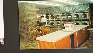 World O' Suds Coin Laundry, 430 E Main St Apopka FL — foto vintage del piso de los primeros años, con mesas y sillas de doblado y una hilera de secadoras junto a la pared de ladrillo
