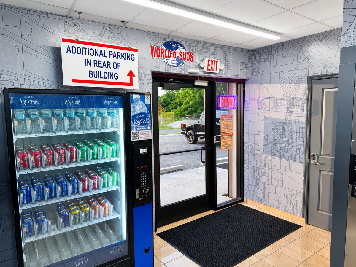 World O' Suds Coin Laundry, 430 E Main St Apopka FL — vestíbulo de entrada con máquina expendedora de Aquafina y el logo de World O' Suds