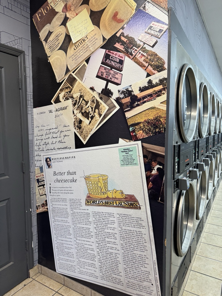 World O' Suds Coin Laundry, 430 E Main St Apopka FL — la pared del legado en 430 E Main St, con el artículo Better Than Cheesecake de Florida Magazine, fotografías vintage y notas escritas a mano de la historia de la tienda