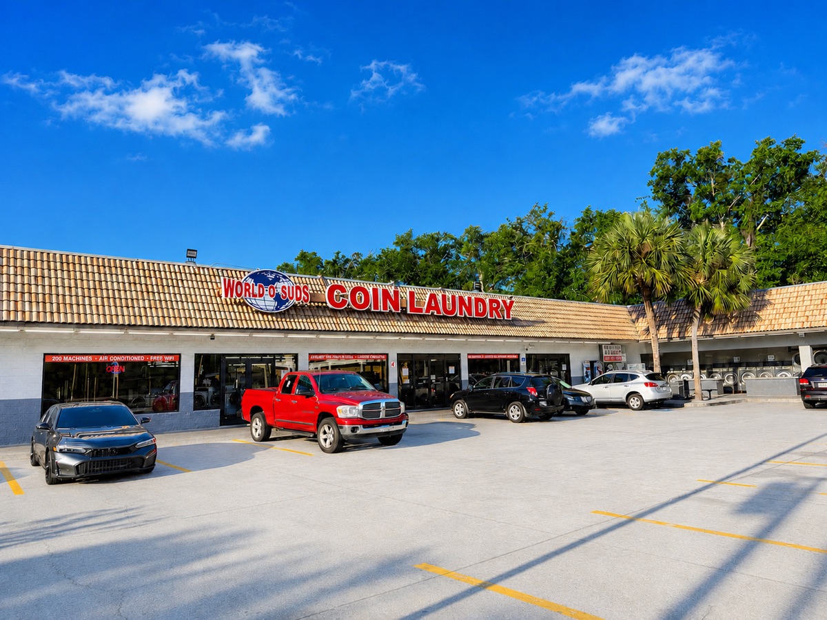 World O' Suds Coin Laundry, 430 E Main St Apopka FL — fachada exterior con cielo azul brillante y estacionamiento lleno